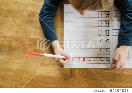Overhead view of boy (4-5) practicing writing letters in workbook 64194838