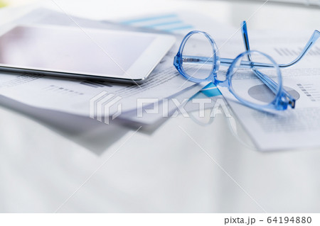 Blue eyeglasses and tablet on business papers 64194880
