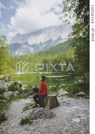 Germany, Bavaria, Eibsee, Woman sitting by Frillensee lake 64195001
