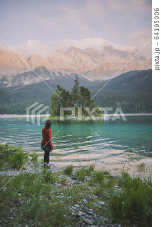 Germany, Bavaria, Eibsee, Young woman standing at shore of Eibsee lake in Bavarian Alps 64195006