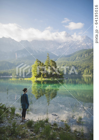 Germany, Bavaria, Eibsee, Young woman standing at shore of Eibsee lake in Bavarian Alps 64195016