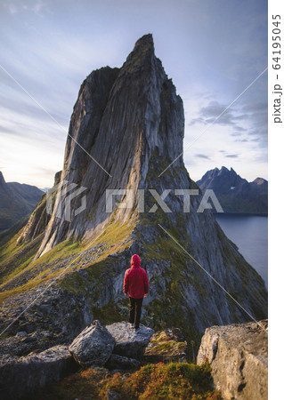 Norway, Senja, Man standing in front of Segla mountain at sunrise 64195045