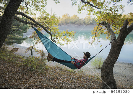 Italy, Man lying in hammock near lake Italy, Man lying in hammock near lake 64195080