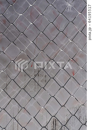 Inverted image of chainlink fence against graffiti covered grey wall, close up 64195517
