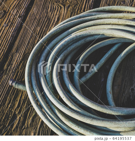 Coiled garden hose on wood decking Coiled garden hose on wood decking 64195537