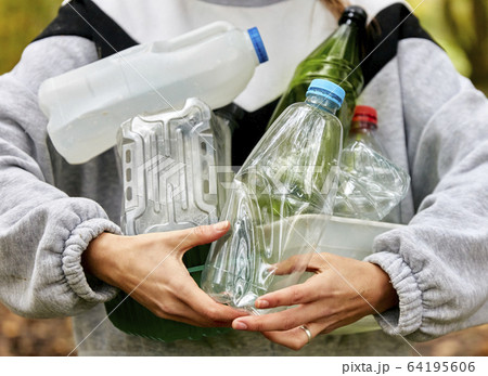Woman holding armful of used plastic packaging and bottles 64195606
