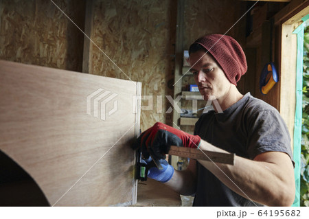 Carpenter using ruler to measure and mark up wood 64195682