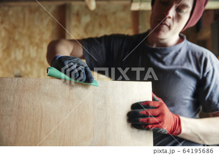 Carpenter sanding down wood for a smooth finish 64195686
