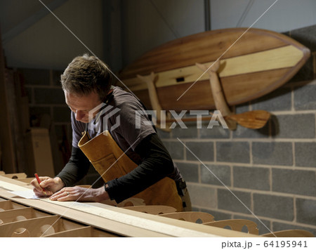 Paddleboard maker using mobile phone in workshop 64195941