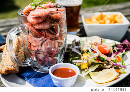 High angle close up of plate of food, prawns in glass jug, side salad, sauce and bread. High angle close up of plate of food, prawns in glass jug, side salad, sauce and bread. 64195951