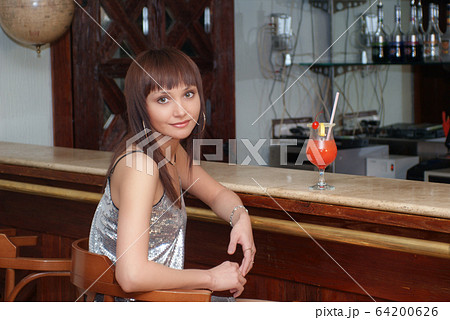 Young beautiful girl with cocktail at the counter in the cafe 64200626