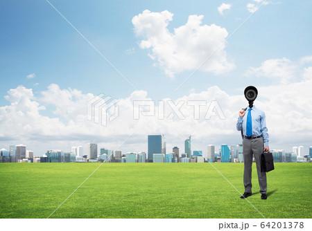 Camera headed man standing on green grass against modern cityscape Camera headed man standing on green grass against modern cityscape 64201378