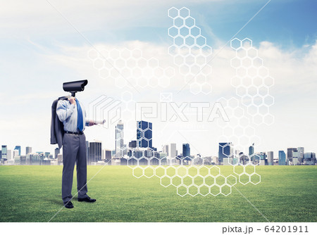 Camera headed man standing on green grass against modern citysca Camera headed man standing on green grass against modern citysca 64201911