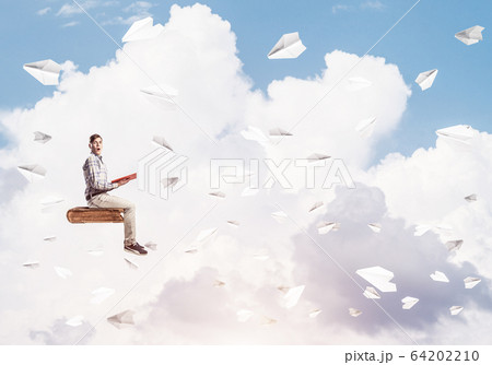 Handsome man student reading book and paper planes flying around 64202210