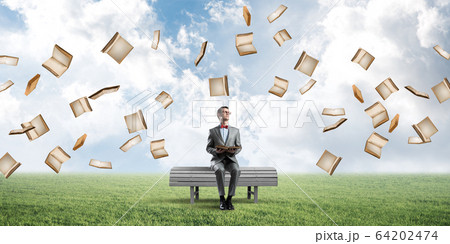 Young businessman or student studying the science and books fly around 64202474