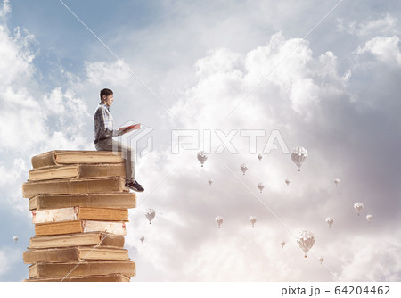 Man student on stack reading book and aerostats flying around Man student on stack reading book and aerostats flying around 64204462