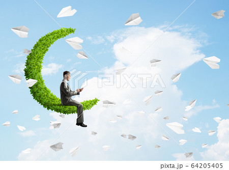 Businessman or student sitting on green moon and making calls Businessman or student sitting on green moon and making calls 64205405