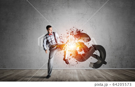Determined banker man in empty concrete room breaking dollar figure Determined banker man in empty concrete room breaking dollar figure 64205573