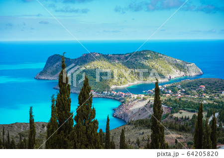 Assos village and coastline of beautiful blue sea. Cypress trees in foreground. Kefalonia island, Greece 64205820