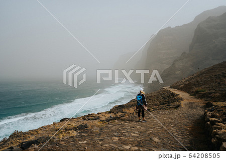Santo Antao, Cape Verde - Female hiker on trail hike Cruzinha da Garca to Ponta do Sol. Moody Atlantic ocean coastline Santo Antao, Cape Verde - Female hiker on trail hike Cruzinha da Garca to Ponta do Sol. Moody Atlantic ocean coastline 64208505