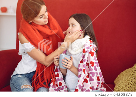 Mother gives her sick daughter hot tea 64208875