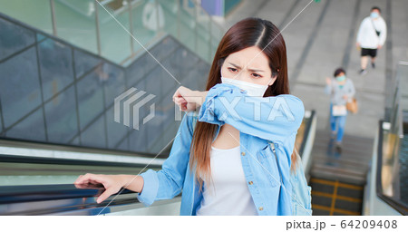 woman coughs in her elbow 64209408