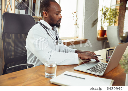 African-american doctor consulting for patient, working in cabinet African-american doctor consulting for patient, working in cabinet 64209494