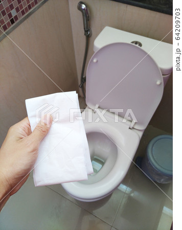 The man's hand touched a toilet paper in order to clean the toilet.For prevent germs and clean at the same time after freeing the alcohol spray. 64209703