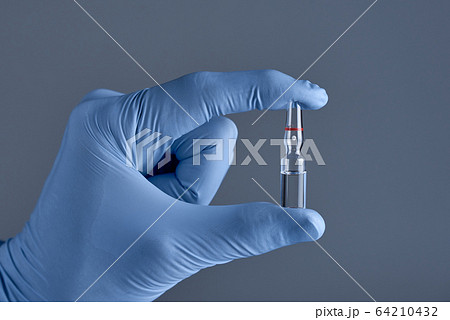 Hand in medical glove holding ampoule. Concept of medical help. Hand in medical glove holding ampoule. Concept of medical help. 64210432