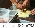 The chef rolling out the dough with his hands 64210758