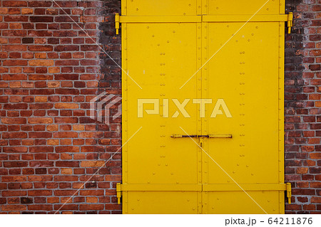 Yellow painted metal door and brick wall background Yellow painted metal door and brick wall background 64211876