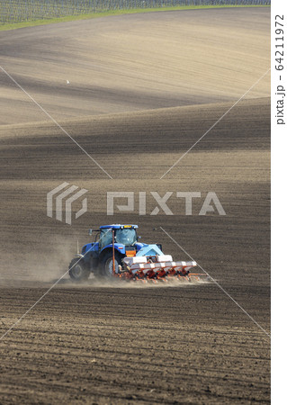 Tractor with seed drill in early spring landscape Tractor with seed drill in early spring landscape 64211972