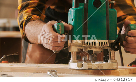 Carpentry industry - man worker cutting out the patterns out of the wooden plank Carpentry industry - man worker cutting out the patterns out of the wooden plank 64212317