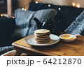 Pancakes with honey on wooden tray in cozy room. 64212870