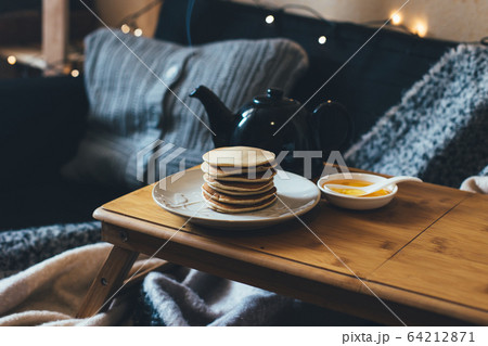Pancakes with honey on wooden tray in cozy room. Pancakes with honey on wooden tray in cozy room. 64212871