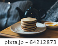 Pancakes with honey on wooden tray in cozy room. 64212873