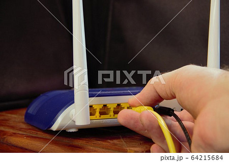 connecting the router to the network cable by plugging in the cable to the back of the wifi router connecting the router to the network cable by plugging in the cable to the back of the wifi router 64215684