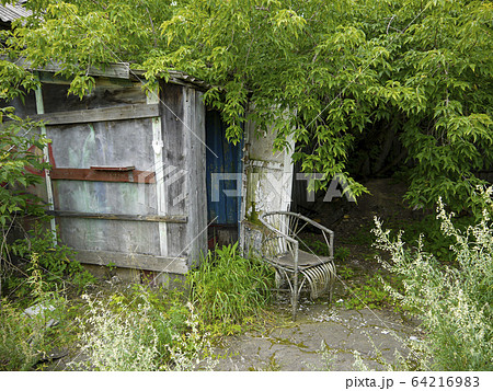 Old armchair near abandoned small house on the edge of the village. Holidays in ecological places in the nature far from big cities. Calm time after beaten the virus. 64216983