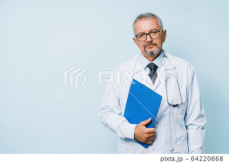 Elderly bearded male doctor in white uniform with a stethoscope with a blue folder. Doctor on the background of a medical research laboratory. Elderly bearded male doctor in white uniform with a stethoscope with a blue folder. Doctor on the background of a medical research laboratory. 64220668