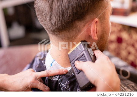 Close up of a male student having a haircut with hair clippers 64221210