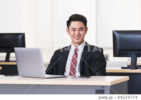 Asian businessman smiling and sittting in office,. Asian businessman smiling and sittting in office,. 64224774