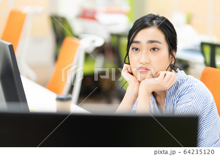 オフィスで不満顔の若い女性社員 オフィスで不満顔の若い女性社員 64235120