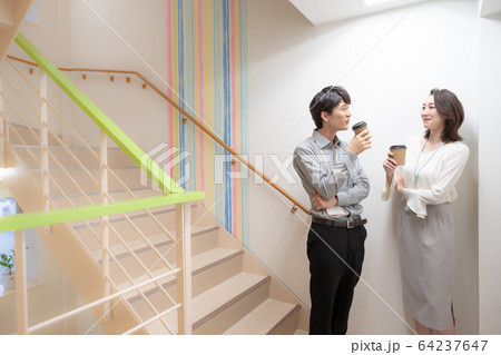 オフィスの廊下で話をする若い男女 64237647