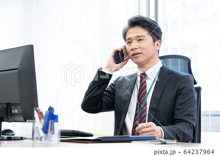オフィスでスマホで話をする部長 64237964