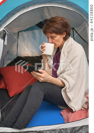 Woman sit inside a tent enjoying a cup of tea 64238860