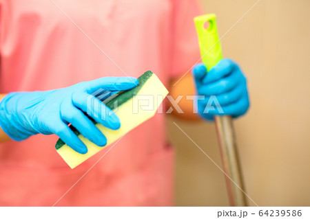 Women hand in a blue rubber glove in the picture, removes and washes bathroom sink by spray and sponge, hygiene concept 64239586