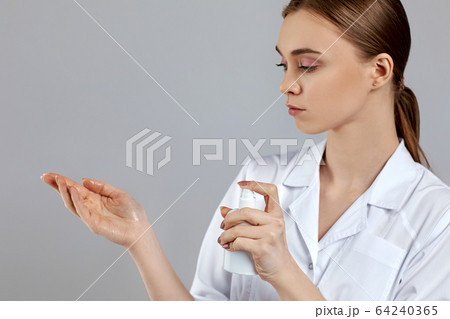 woman doctor in white uniform using sanitizer dispenser 64240365