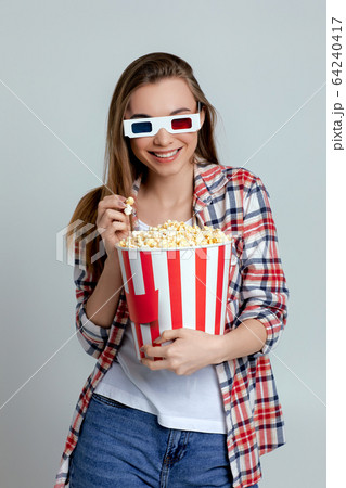beautiful young woman eating popcorn from bucket 64240417
