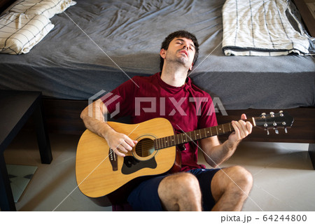 Man playing guitar in his bedroom and spending 64244800