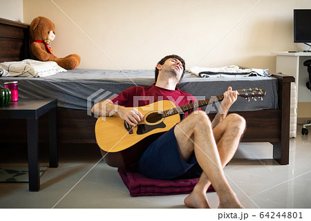 Man playing guitar in his bedroom and spending 64244801